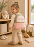 Toddler wearing a personalized pink mini backpack with custom name embroidery in a cozy nursery room