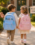 Two children walking to school wearing personalized blue and pink quilted backpacks with custom name embroidery